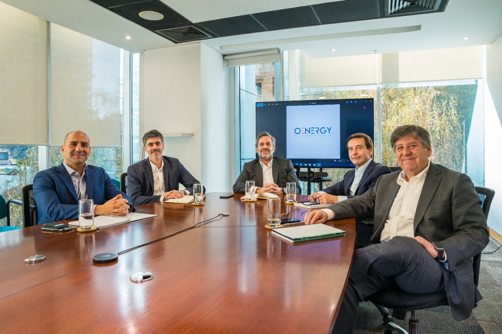 Reunión de directorio en sala de juntas con logo oEnergy en pantalla